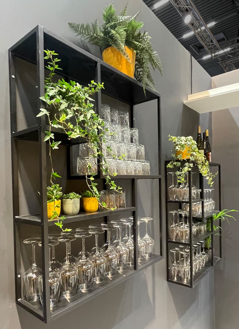 Regale mit Gläsern und Pflanzen in der Bar auf dem Sika Hauptstand auf der Messe Bau 2025 in München