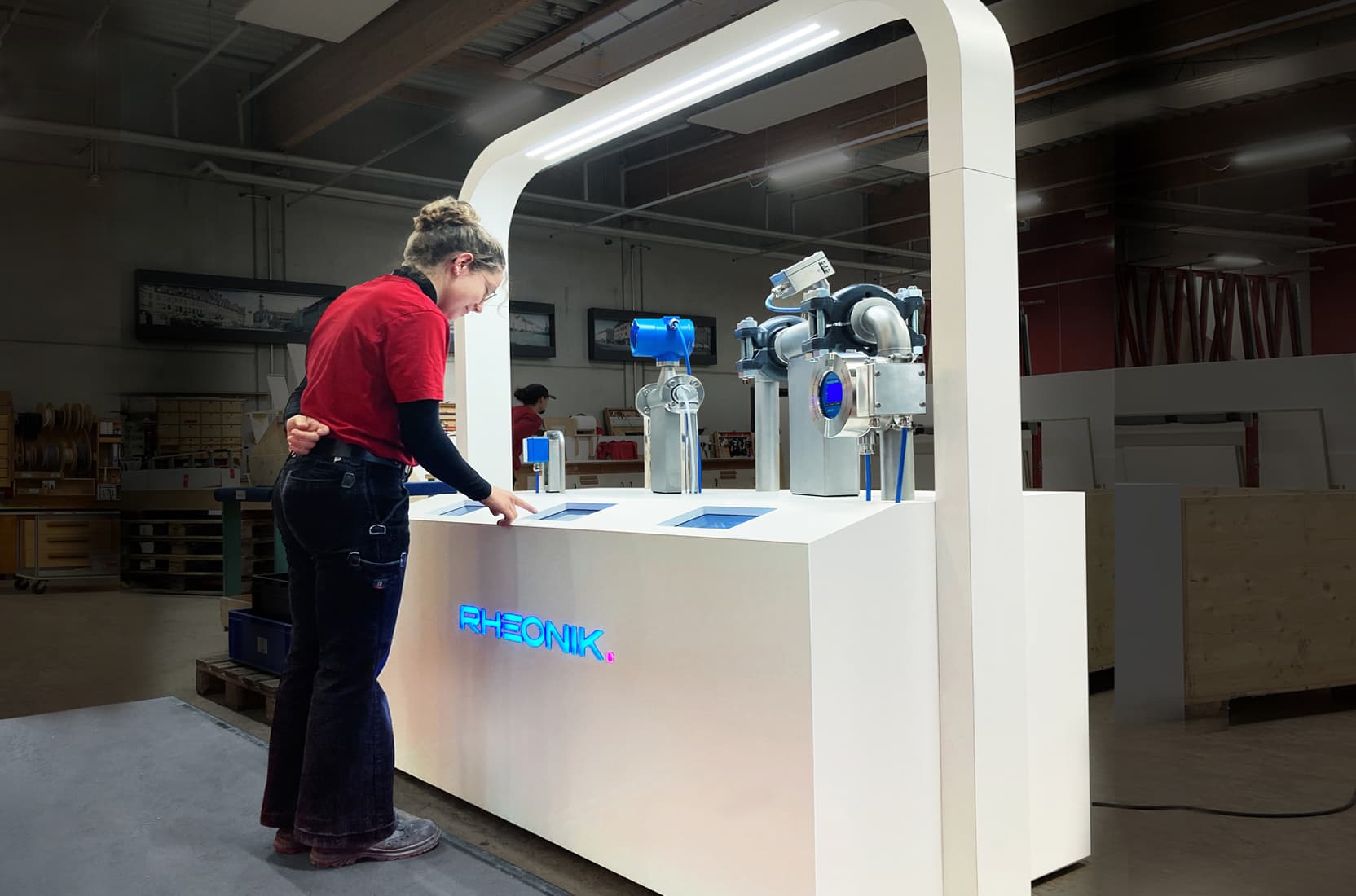 Mitarbeiterin von deka messebau steth an einem modernen, technischen Exponat und liest den Text auf einem Display